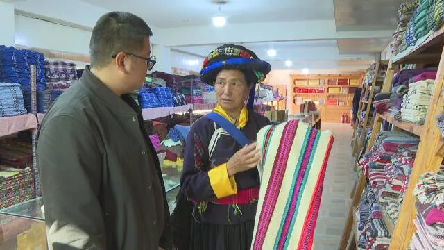 阿七独支玛向客人展示纺织手工艺品。 (丽江融媒记者 赵丽军 摄)